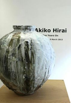 a large vase sitting on top of a wooden table in front of a white wall