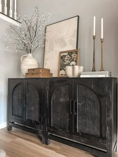 a black cabinet sitting on top of a hard wood floor next to a white vase