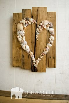 an image of a heart made out of seashells on a piece of wood