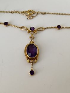 A lovely antique Art Nouveau amethyst necklace in a rich 14 karat buttery yellow gold mounting. This delicate design is a little Gem with it's simple yet very elegant design centered around an antique, faceted, deep purple, oval amethyst. The fine chain has stations of 6 round bezel set amethysts who's color matches the intense purple of the center stone. The sizes are slightly tapered for a beautiful symmetry  There is an extra safety link chain to reinforce the strength of this delicate piece. Vintage Amethyst Necklace, Cheap Antique Oval Jewelry, Oval Amethyst Pendant, Antique Jewelry Silver, Gold And Purple Necklace, Formal Purple 14k Gold Necklace, Classic Oval Amethyst Necklaces, Antique Round Purple Necklace, Antique Amethyst Jewelry Stamped 14k