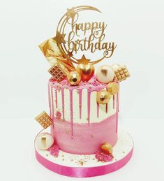 a pink and white birthday cake with gold decorations