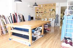 a room filled with lots of different types of fabrics on shelves next to a wooden table