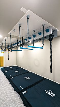 an empty room with blue mats on the floor and ropes hanging from the ceiling above