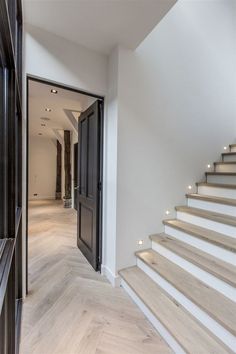 an open door leading to a white staircase with wooden handrails and light wood flooring