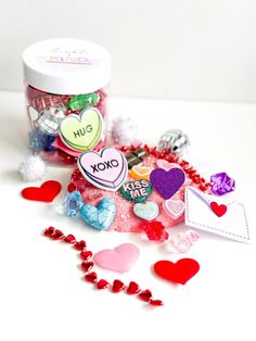 a jar filled with lots of different types of candies next to a heart shaped object