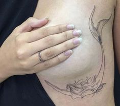 a woman's stomach with a flower tattoo on her left side, and a ring in her right hand