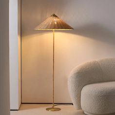 a lamp that is sitting next to a chair in a room with a white wall