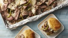 two small plates with sandwiches on them next to a pan of meat and cheese covered bread