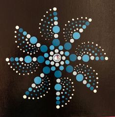 a painting of a blue and white snowflake on a black background with polka dots