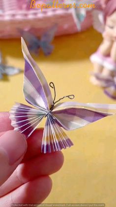 a hand holding a small purple and white butterfly