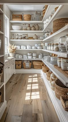 an open pantry filled with lots of white dishes and wicker baskets on the shelves