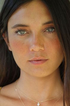 a close up of a woman wearing a necklace with a cross on it's neck