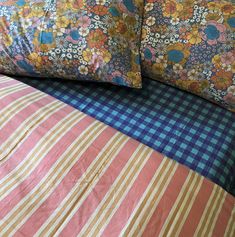 a bed with two pillows on top of it next to a pillow case and plaid bedspread