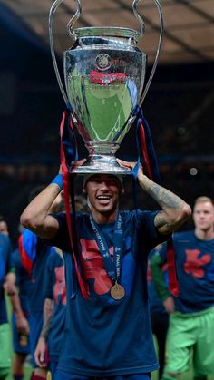 a man holding up a silver trophy on top of his head with other men in the background