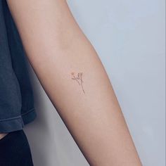 a woman's arm with a small flower tattoo on the left side of her arm