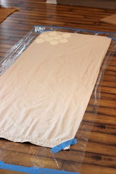 a large sheet of white paper on top of a wooden floor with blue tape around it