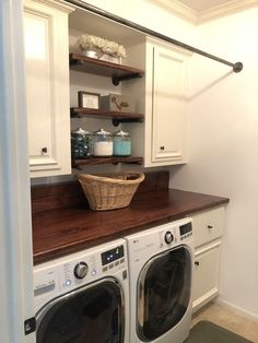 a washer and dryer in a room with white cupboards, shelves and drawers