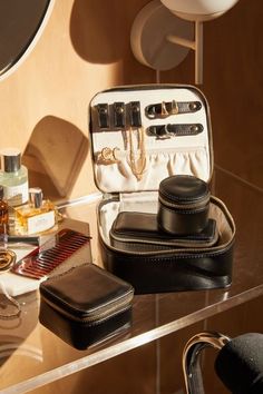 an open suitcase sitting on top of a table filled with cosmetics and other items next to a mirror