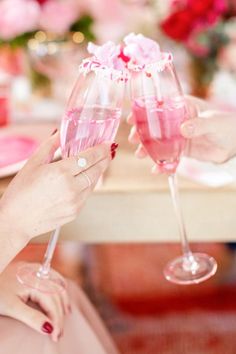 two people toasting with pink wine glasses