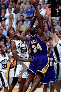 the basketball players are trying to block the ball from going into the basket during a game