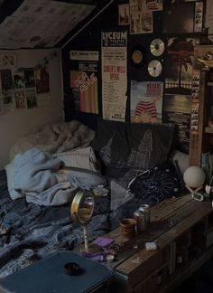 a messy bedroom with lots of clutter on the bed and walls covered in posters