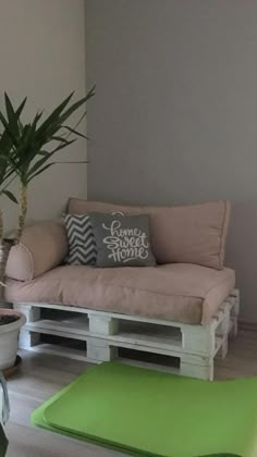 a couch made out of pallets and some plants in the corner with a potted plant next to it