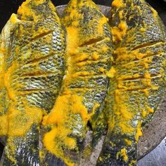 three pieces of fish with yellow sauce on it's side, sitting in a pan