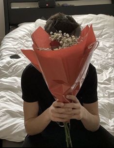 a woman sitting on a bed with a bouquet of flowers in front of her face