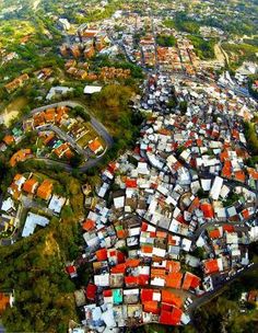 an aerial view of a city with lots of red and white houses on the hillside