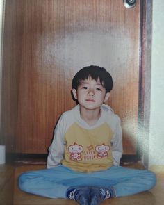 a young boy sitting on the floor in front of a door