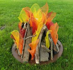 a fire pit made out of branches and mesh wrapped around it in the middle of some grass