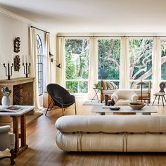 a living room filled with lots of furniture and large windows overlooking the trees in the distance