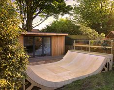 a skateboard ramp is in the middle of a backyard with trees and a shed behind it