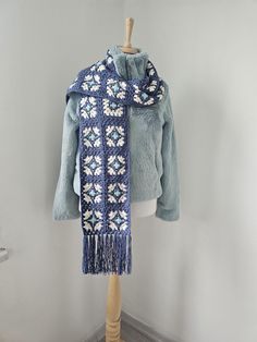 a blue jacket and scarf on a mannequin stand in front of a white wall