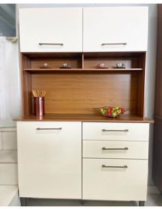 a kitchen with white cabinets and wooden counter tops in the center is a bowl of fruit