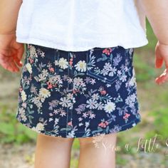 a close up of a child's skirt with flowers on it and the bottom part of her leg