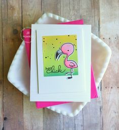 a card with a pink flamingo on it sitting on top of a white plate