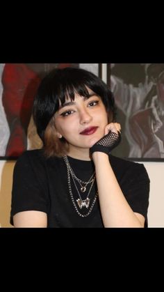 a woman in black shirt holding her hand up to her face and looking at the camera