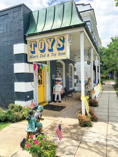 a toy store with an american flag on the front door and flowers in pots outside