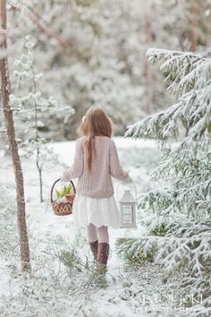 a girl walking in the snow carrying a basket