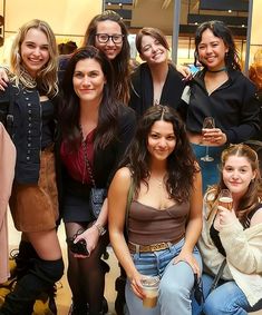 a group of women standing next to each other in front of a clothing store window