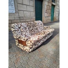 a couch sitting on the side of a street next to a brick wall and green door