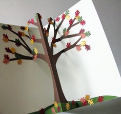 an open card with a tree made out of paper and colored autumn leaves on it