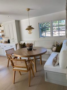 a living room and dining area with white couches, wooden table and chairs in it