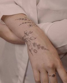 a woman's hand with a flower tattoo on her left wrist and the other arm