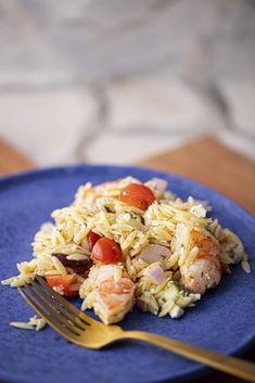 a blue plate topped with rice covered in meat and veggies next to a fork