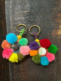 multicolored pom - pom keychain on wooden surface with metal hook