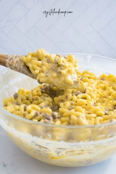 a bowl full of macaroni and cheese with a wooden spoon in the middle