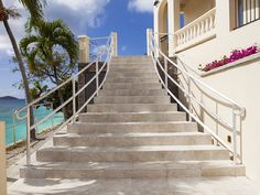 stairs leading up to the beach with palm trees and blue water in the back ground