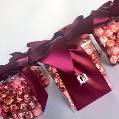 three boxes filled with pink and red candies on top of a white table next to each other